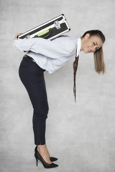 Zakenvrouw draagt een zware koffer op haar rug — Stockfoto