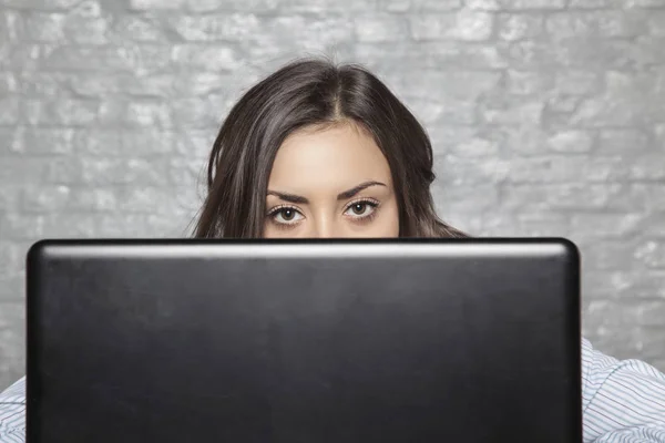 The young secretary hides behind the monitor — Stock Photo, Image