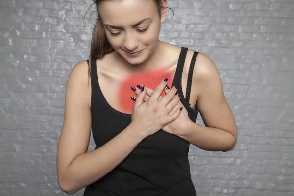 Una mujer joven sostiene su pecho, Posible ataque al corazón u otros —  Fotos de Stock