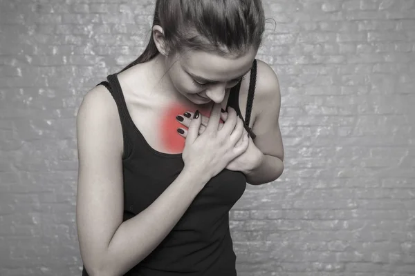 一个年轻的女人抱着她的胸膛。可能的心脏病发作 — 图库照片