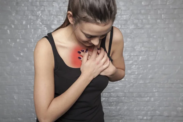 Una mujer joven sostiene su pecho, Posible ataque al corazón, primero —  Fotos de Stock