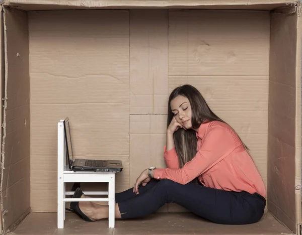 Zakenvrouw gaat zitten in een kartonnen Bureau — Stockfoto