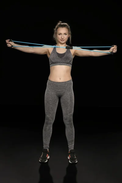 Atletik bir kadının önünde, elastik kauçuk uzanır — Stok fotoğraf