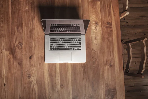 Деревянный стол в офисе, ноутбук на нем, вид сверху — стоковое фото