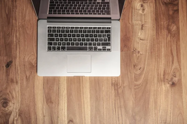 Деревянный стол в офисе, ноутбук на нем — стоковое фото