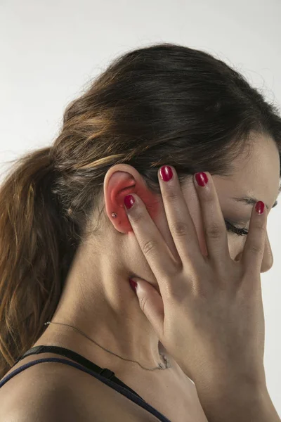 Eine junge Frau kämpft mit Schmerzen, isoliert im Hintergrund — Stockfoto