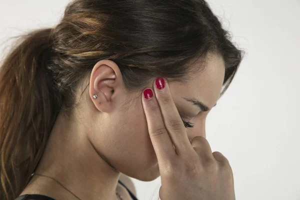 Une jeune femme est aux prises avec la douleur, isolée sur le fond — Photo