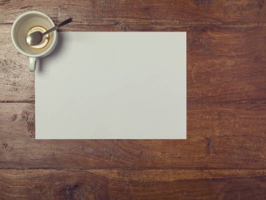 Kahve fincanı, masa manzarası ve boş bir kağıt parçası.