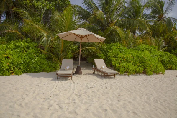 Шезлонги под зонтиками на пляже на Мальдивах — стоковое фото