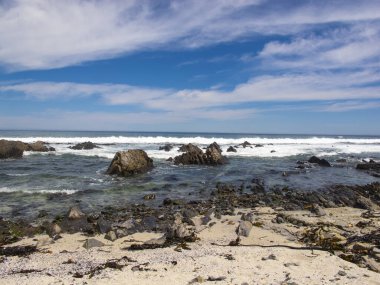 Taş sahil, mavi su ve güzel gökyüzü.