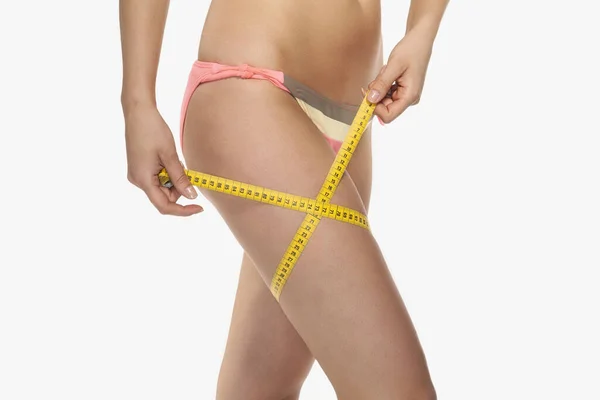 A woman with a perfect figure uses a measuring tape to measure h — Stock Photo, Image