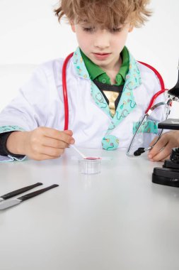 Genç doktor cam bir sürgüye kan örneği koyar.