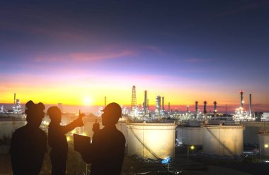 Petrol rafinerisinde çalışan mühendis ekibinin silueti.
