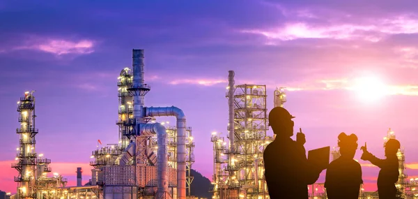 Petrol rafinerisinde çalışan mühendis ekibinin silueti.