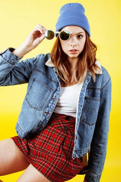 young pretty teenage woman emotional posing on yellow background, fashion lifestyle people concept