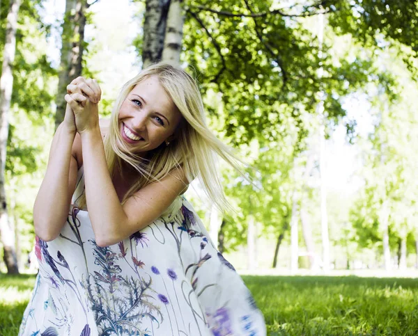 happy blond young woman in park smiling