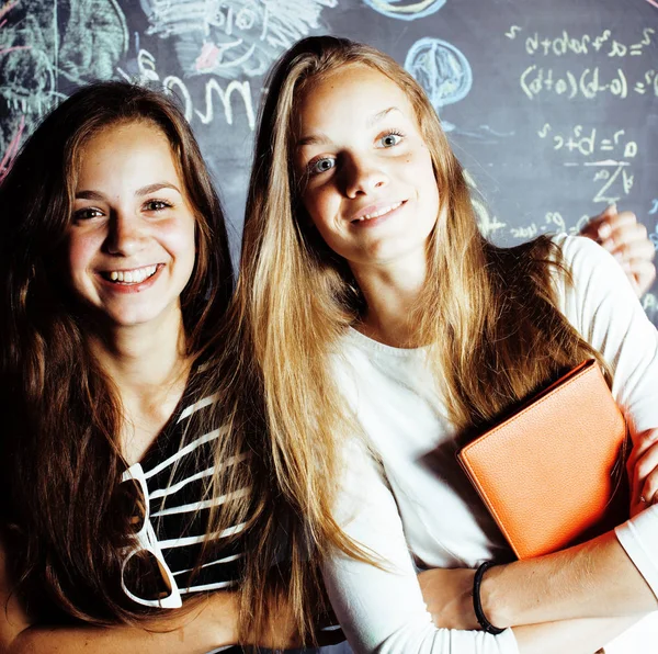 back to school after summer vacations, two teen real girls in classroom with blackboard painted together, lifestyle people concept