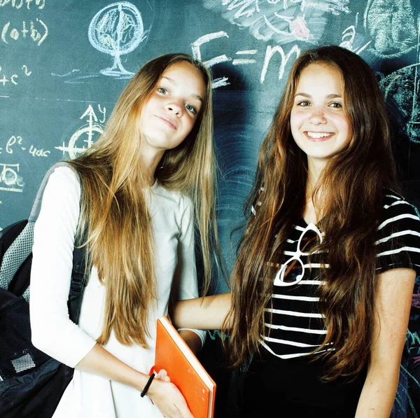 back to school after summer vacations, two teen real girls in classroom with blackboard painted together, lifestyle real people concept