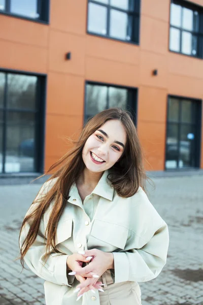 young pretty teenage girl posing cheerful happy smiling wearing street style outside in europe city, lifestyle people concept