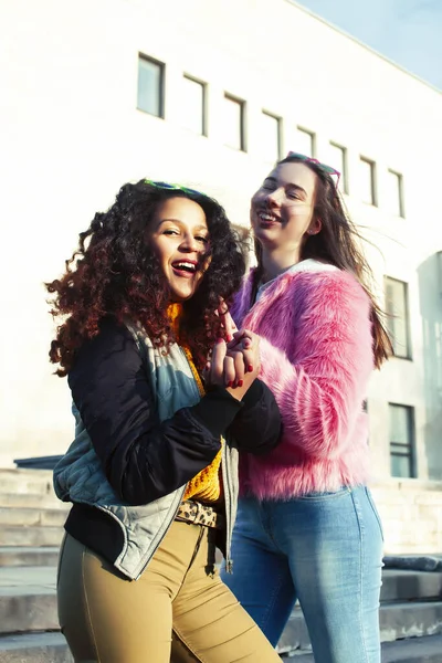 two pretty student girlfriends happy smiling outside at university building, caucasian and african woman, lifestyle people concept