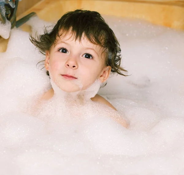 Little cute boy in bathroom with bubbles close up, lifestyle real