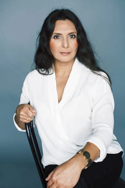 pretty brunette confident mature woman sitting on chair in studio, lifestyle people concept