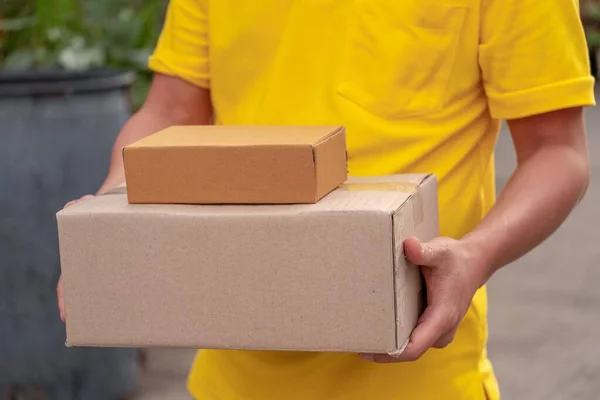 Gelber Zusteller trägt Pakete. — Stockfoto