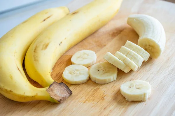 Kesme tahtasında muz dilimliyor. Taze kesilmiş muz. Vitamin al..