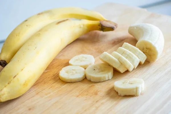 Kesme tahtasında muz dilimliyor. Taze kesilmiş muz. Vitamin al..