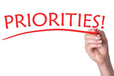 El, saydam beyaz arkaplanda kırmızı işaretli sözcük öncelikleri yazar.