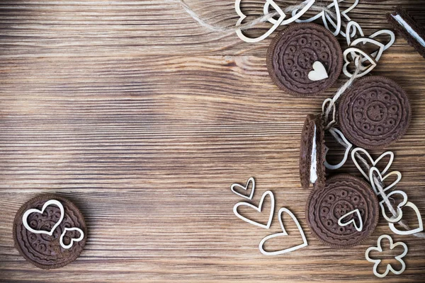chocolate cookie sandwich on a wooden surface. hearts made of wood are strung on a rope. happy Valentine\'s day. beautiful picture with biscuits. wooden background. texture.