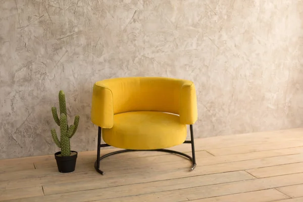 Интерьер комнаты с желтым стулом, на стене декоративная штукатурка, кактус в кастрюле рядом со стулом — стоковое фото