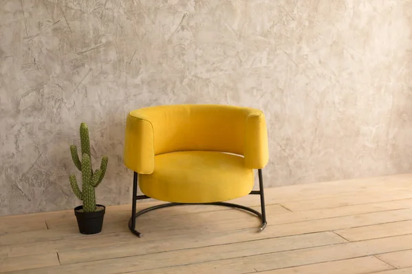 房间里有一把黄色的椅子，墙上挂着装饰用的石膏，椅子旁边的罐子里有仙人掌 — 图库照片#