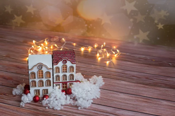 Beautiful toy wooden houses on a wooden background with garlands