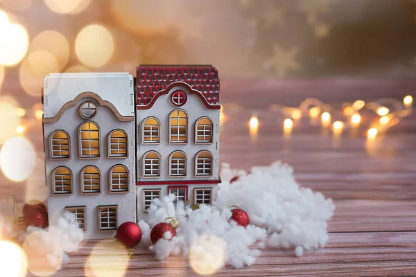 Beautiful toy wooden houses on a wooden background with garlands