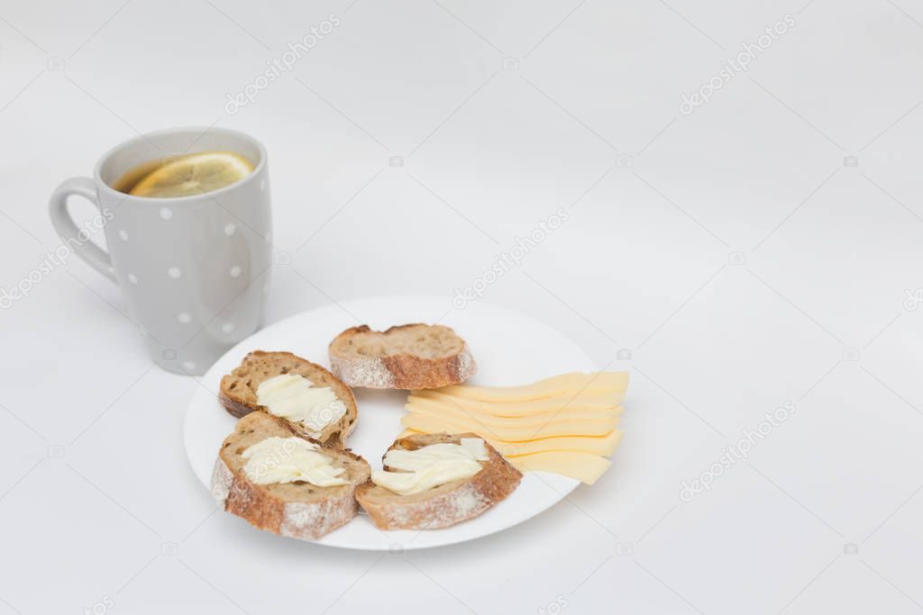 Tea with lemon, sliced bread with cheese and sandwiches