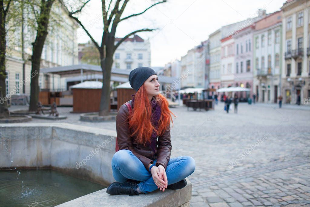 Red-haired girl in the town square at the fountain