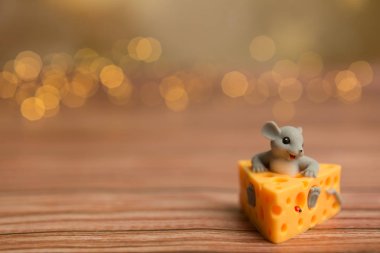 Oyuncak bir fare ahşap yıldızlı arka planda peynirin içinde oturuyor, 2020 'nin bir sembolü..