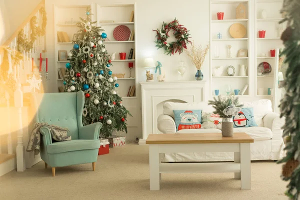 Wnętrze sali bożonarodzeniowej, biała sofa z poduszkami przy stoliku i niebieskie krzesło. — Zdjęcie stockowe