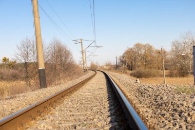 Demiryolu manzarası var. Demiryolu rayları yükseliyor. Tren yolu uzaklarda kayboluyor..