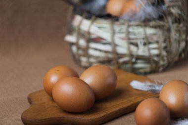 Kahverengi arka planda taze tavuk yumurtası ve sepet.