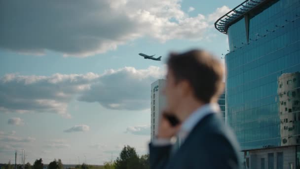 Aeronave a descolar. Bonito homem vestido formal falando smartphone. Homem vendo a mão acenando — Vídeo de Stock