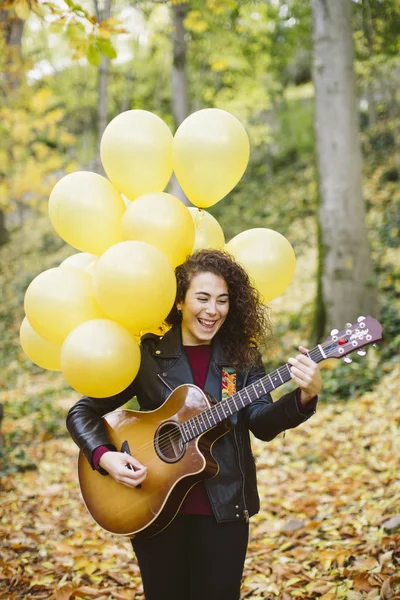 Piękna młoda kobieta gra na gitarze w lesie. — Zdjęcie stockowe