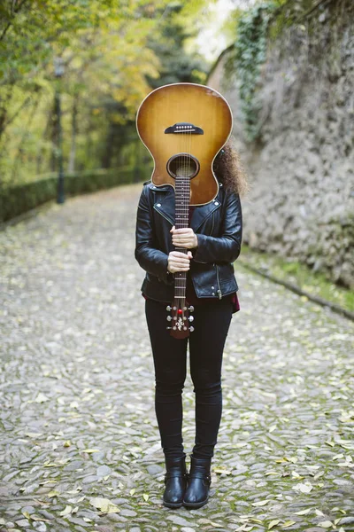 Piękna młoda kobieta zasłaniając twarz z gitarą. — Zdjęcie stockowe