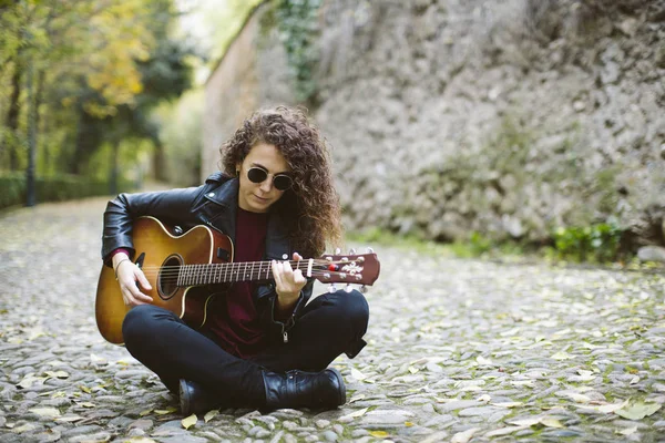 Piękna młoda kobieta gra na gitarze w lesie. — Zdjęcie stockowe