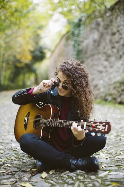 Piękna młoda kobieta, patrząc na kamery z gitarą. — Zdjęcie stockowe