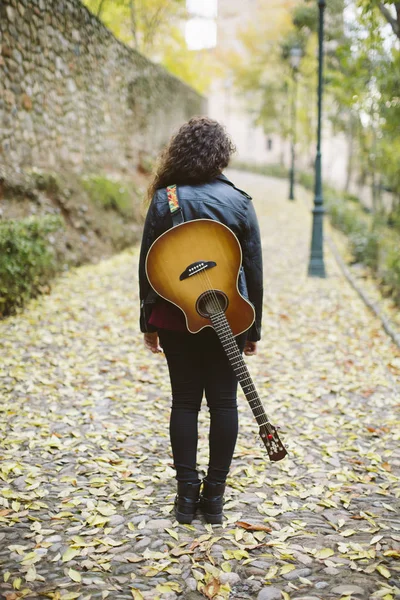 Piękna młoda kobieta stojąc do tyłu z jej gitara. — Zdjęcie stockowe