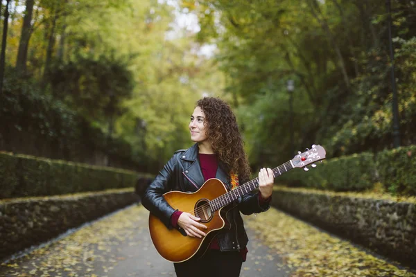Piękna młoda kobieta gra na gitarze w lesie. — Zdjęcie stockowe
