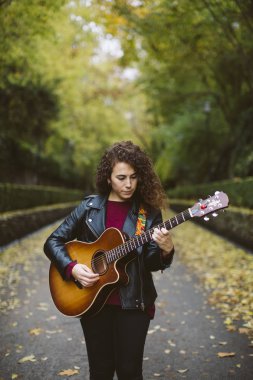 Güzel genç kadın üzerinde orman gitar çalmak.