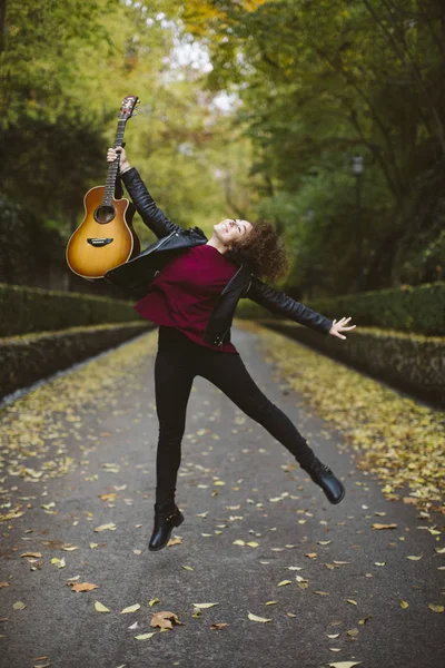 Piękna młoda kobieta, skoki z jej gitara w lesie. — Zdjęcie stockowe